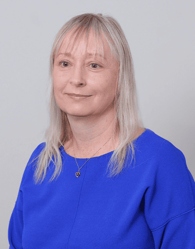 Professional woman with blonde hair wearing a blue top, representing Gresham House's investment team and expertise in sustainable and alternative asset management.