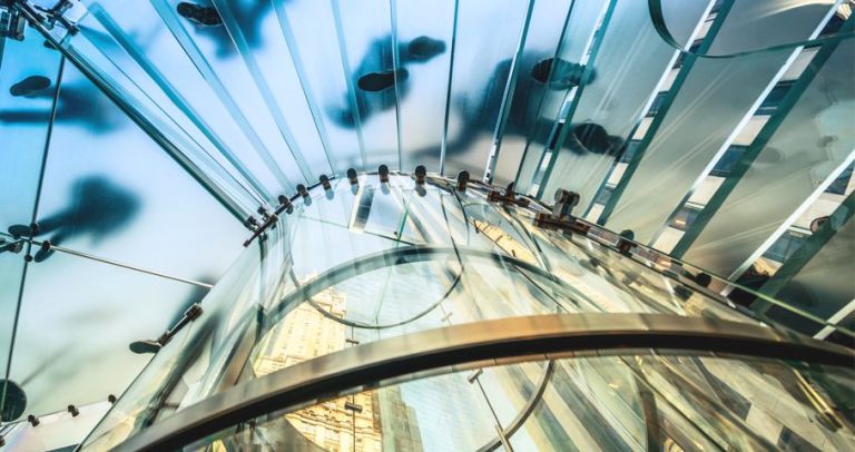 A bottom view to the man walking on transparent glass stairs