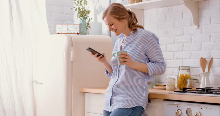 Woman looking at the phone in the kitchen