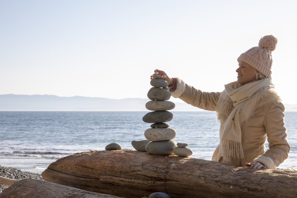 Woman balances rocks on the beach