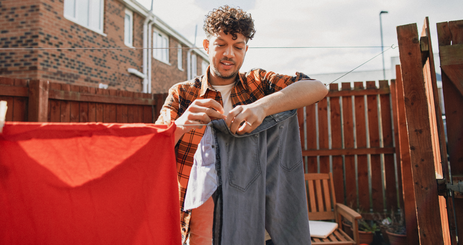 A man spreads laundry in the yard of the house