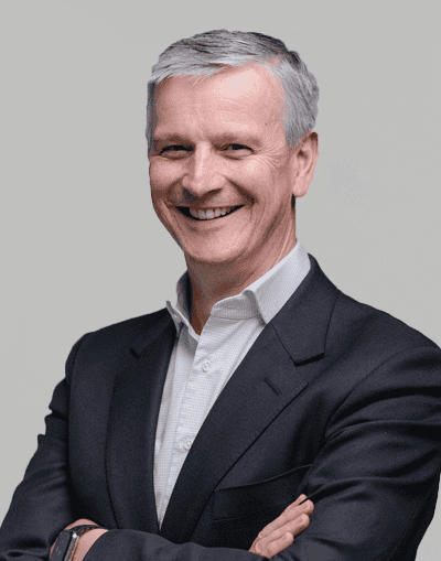 Senior male executive in formal business attire smiling confidently at Gresham House investment firm.