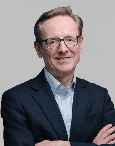 A professional portrait of a confident businessman in a suit and glasses, representing Gresham House's expertise in investment management and sustainable asset classes.