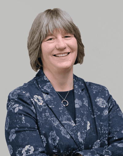 Experienced female professional smiling, wearing a floral blazer, representing Gresham House's commitment to sustainable investment and innovative financial solutions in the UK.