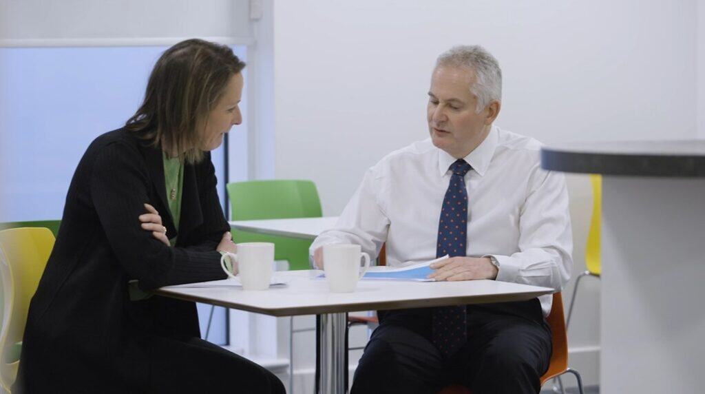 Gresham House investment professionals discussing strategy in a modern office environment with colourful chairs and white walls, emphasising expertise in alternative investments and sustainability.
